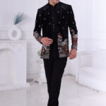 Man wearing a black velvet embroidered bandhgala with silver and maroon elephant and floral motifs.