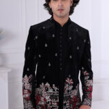 Man wearing a black velvet embroidered bandhgala with silver and maroon elephant and floral motifs.