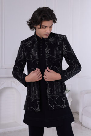 Man wearing a black Jodhpuri suit with sequin embroidery in geometric and floral design.