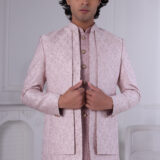 Man wearing a blush pink embroidered Jodhpuri suit with delicate detailing.