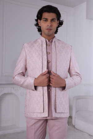 Man wearing a blush pink embroidered Jodhpuri suit with delicate detailing.