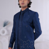 Man wearing a navy blue embroidered Jodhpuri suit with thread and sequin detailing.