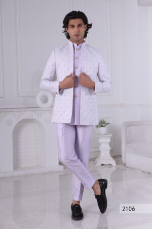 Man dressed in a lavender Jodhpuri suit with a diamond pattern, featuring a high collar and buttoned front, set in a minimalist interior with white walls.