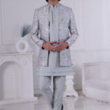 Man wearing a pastel blue floral embroidered Jodhpuri suit with matching kurta and trousers, posing indoors with hands clasped.