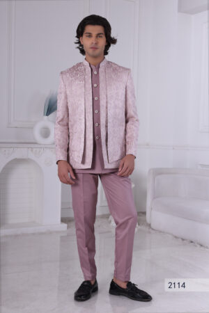 Man wearing a lavender textured Jodhpuri suit with subtle embroidery and metallic buttons, standing indoors with hands clasped.