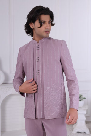 Man wearing a lavender embroidered Jodhpuri suit with vertical patterns and detailed hem design, posing indoors.