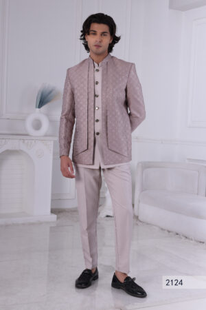 Man wearing a pastel pink textured Jodhpuri suit with metallic buttons, standing with hands clasped.