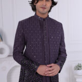 Man wearing a deep purple Jodhpuri suit with vertical sequin patterns and floral embroidery on sleeves and hem.