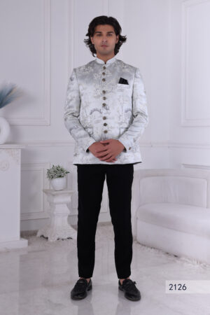 Man wearing a silver brocade Jodhpuri suit with intricate patterns, ornate buttons, and a black pocket square.