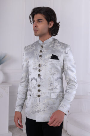 Man wearing a silver brocade Jodhpuri suit with intricate patterns, ornate buttons, and a black pocket square.