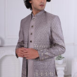Man wearing a grey embroidered Jodhpuri suit with metallic detailing and ornate buttons.