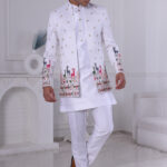 Man wearing a white Jodhpuri suit featuring golden embroidery and colorful deer motifs on the cuffs and hemline.