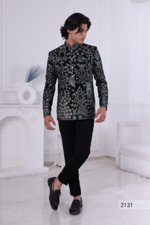 Man wearing a dark green velvet Jodhpuri suit with intricate floral, peacock, and dome embroidery.
