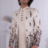 Man wearing an ivory Jodhpuri suit with maroon and black floral embroidery.