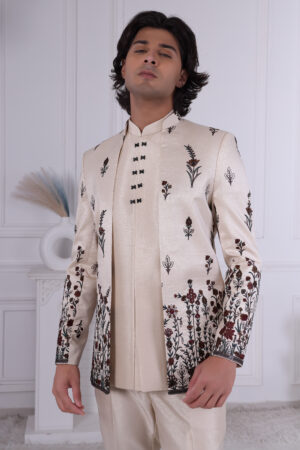 Man wearing an ivory Jodhpuri suit with maroon and black floral embroidery.