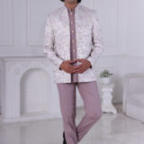 Man wearing a pastel lavender Jodhpuri suit with brocade deer and foliage motifs.