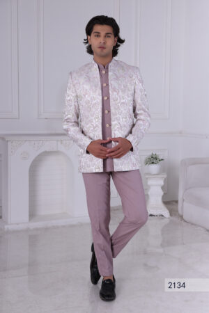 Man wearing a pastel lavender Jodhpuri suit with brocade deer and foliage motifs.