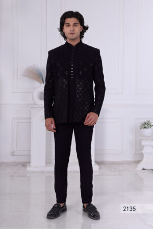 Man wearing a midnight black textured Jodhpuri suit with geometric patterns and metallic button detailing.