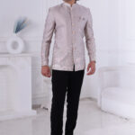 Man wearing an ivory silk embroidered Jodhpuri suit with pastel floral and elephant motifs.