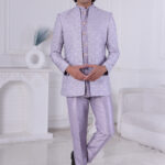 Man wearing a lavender silk brocade Jodhpuri suit with gold button detailing.