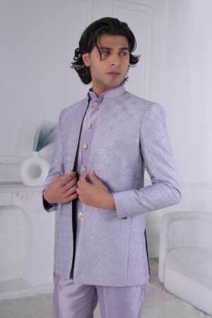 Man wearing a lavender silk brocade Jodhpuri suit with gold button detailing.