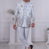 Man wearing an ice-blue Jodhpuri suit with detailed floral embroidery and silver buttons.