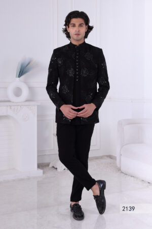 Man wearing a black Jodhpuri suit with floral embroidery, sequin highlights, and metallic triangular buttons.