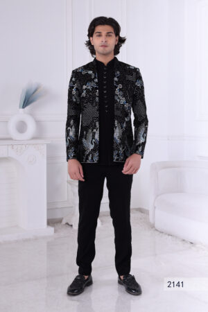 Man wearing a black velvet Jodhpuri suit with silver and blue crane embroidery and floral detailing.