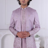 A man wearing a lavender Jodhpuri suit with metallic embroidery on the sleeves and hem, paired with a matching kurta and trousers.