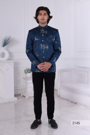 A man wearing a royal blue embroidered Jodhpuri suit with horse and crane motifs, styled with metallic buttons.