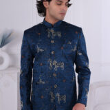 Man wearing a royal blue embroidered Jodhpuri suit with horse and crane motifs, styled with metallic buttons.