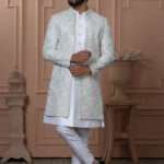 Men’s ivory white Indo-Western outfit with embroidered jacket and golden button kurta.
