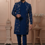 Man wearing navy blue Indo-Western outfit with floral embroidered long jacket.