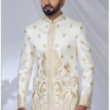 Man wearing an ivory white Jodhpuri suit with golden peacock and floral embroidery, styled with a mandarin collar.