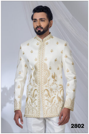 Man wearing an ivory white Jodhpuri suit with golden peacock and floral embroidery, styled with a mandarin collar.