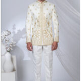 Man wearing an ivory white Jodhpuri suit with golden peacock and floral embroidery, styled with a mandarin collar.