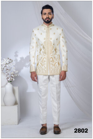 Man wearing an ivory white Jodhpuri suit with golden peacock and floral embroidery, styled with a mandarin collar.