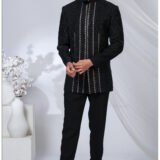 Man wearing a black Jodhpuri suit with geometric embroidered detailing in silver and black, styled with a mandarin collar