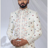 Man wearing an ivory embroidered Jodhpuri suit with multicolored floral motifs and mandarin collar.