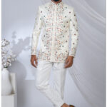 Man wearing an ivory embroidered Jodhpuri suit with multicolored floral motifs and mandarin collar.