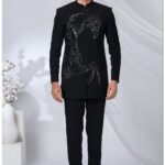 Man wearing a black Jodhpuri suit with an embroidered sequined horse design and mandarin collar.