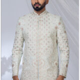 Man wearing a pastel embroidered Jodhpuri suit with intricate floral and geometric patterns and mandarin collar.