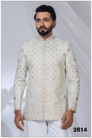 Man wearing a pastel embroidered Jodhpuri suit with intricate floral and geometric patterns and mandarin collar.