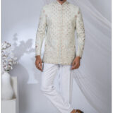 Man wearing a pastel embroidered Jodhpuri suit with intricate floral and geometric patterns and mandarin collar.