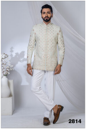 Man wearing a pastel embroidered Jodhpuri suit with intricate floral and geometric patterns and mandarin collar.