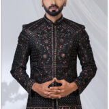 Man wearing a black embroidered Jodhpuri suit with intricate red and gold threadwork and mandarin collar.