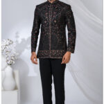 Man wearing a black embroidered Jodhpuri suit with intricate red and gold threadwork and mandarin collar.