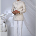 Man wearing an ivory Jodhpuri suit with pearl embroidery, floral motifs, and a mandarin collar.