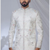 Man wearing an ivory Jodhpuri suit with pastel floral and geometric embroidery and a mandarin collar.