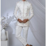 Man wearing an ivory Jodhpuri suit with pastel floral and geometric embroidery and a mandarin collar.